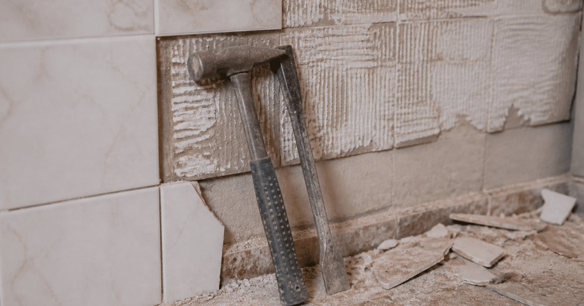 Outils enleves carrelage mural, marteau burin appuyes contre tuile