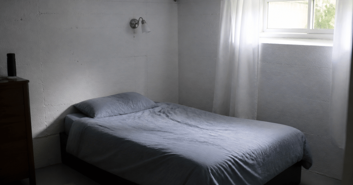 Lit simple contre mur de sous-sol amenage en chambre