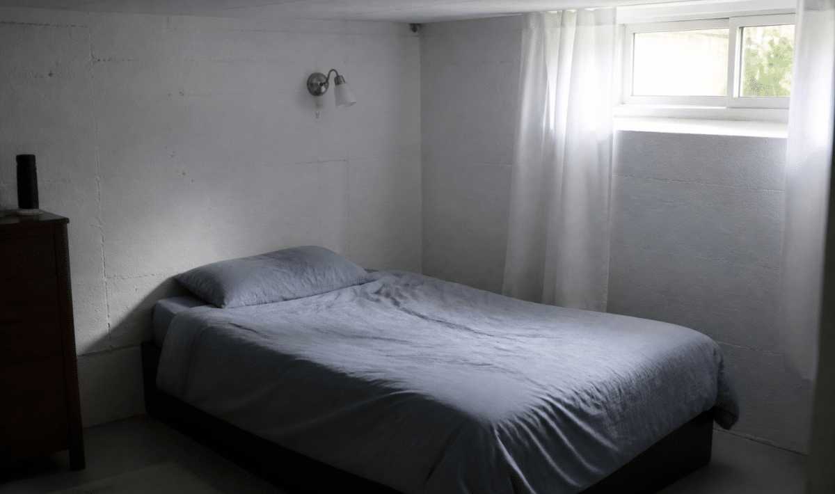Lit simple contre mur de sous-sol amenage en chambre