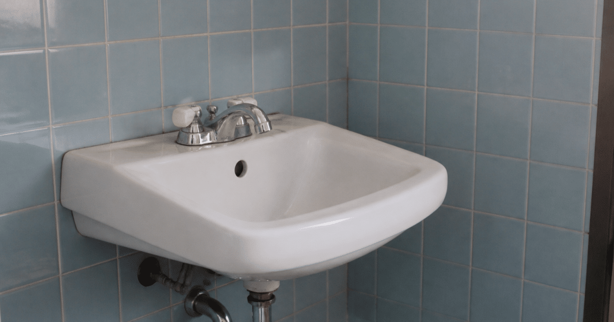 Petit lavabo blanc contre mur carrelé bleu clair