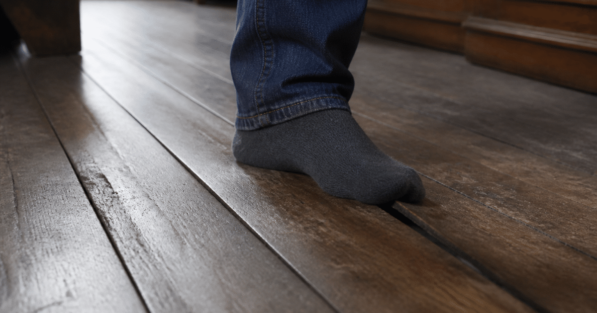 Plancher en bois ancien s'enfonçant légèrement sous le poids d'un pied