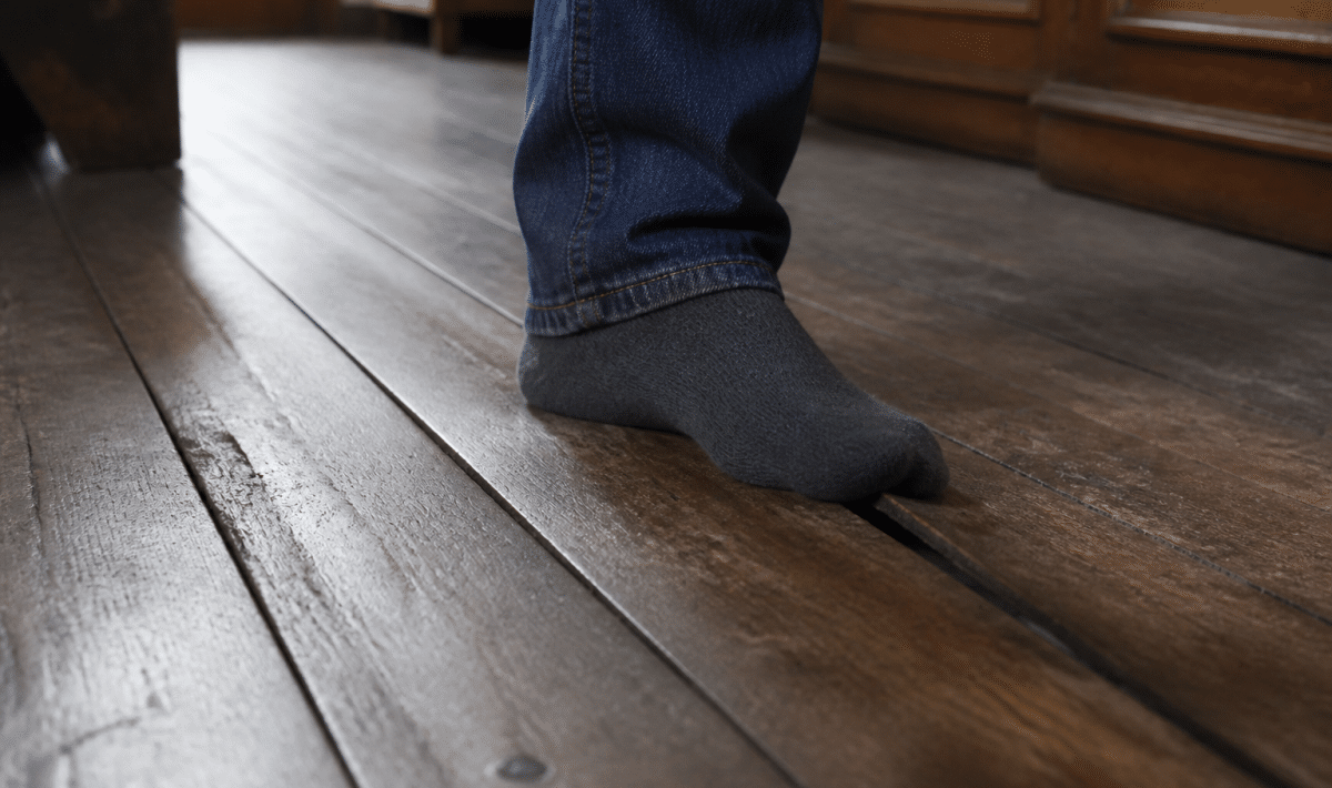 Plancher en bois ancien s'enfonçant légèrement sous le poids d'un pied