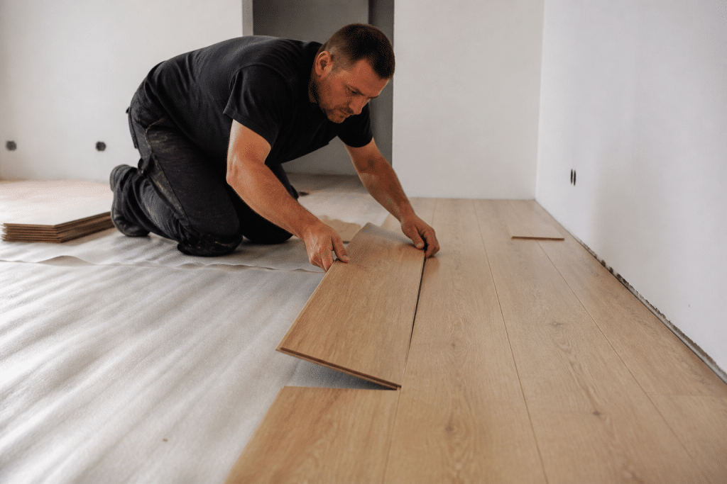Ouvrier pose parquet flottant brun clair sol interieur