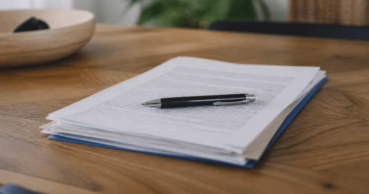 Contrat immobilier signé avec stylo posé dessus, documents empilés