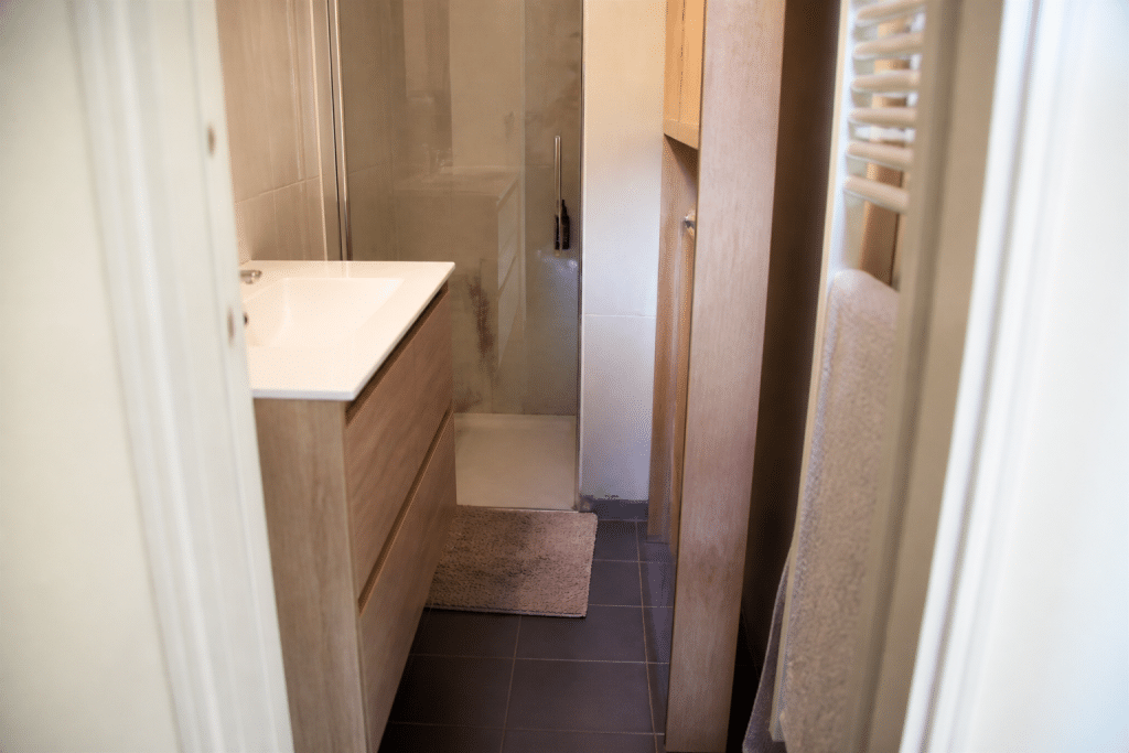 Petite salle de bain encombrée avec meubles serrés et passage etroit