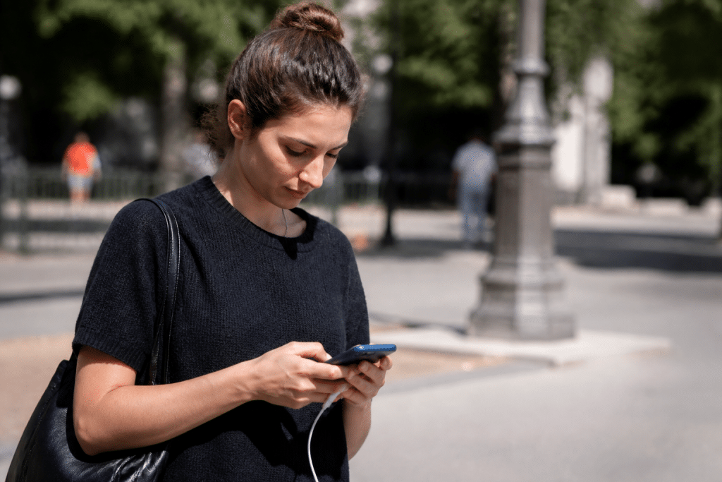 Personne tenant telephone charge en plein jour urbain