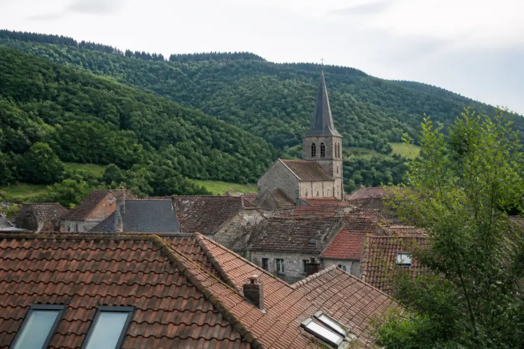 Toits de tuiles rouges, clocher et colline verte